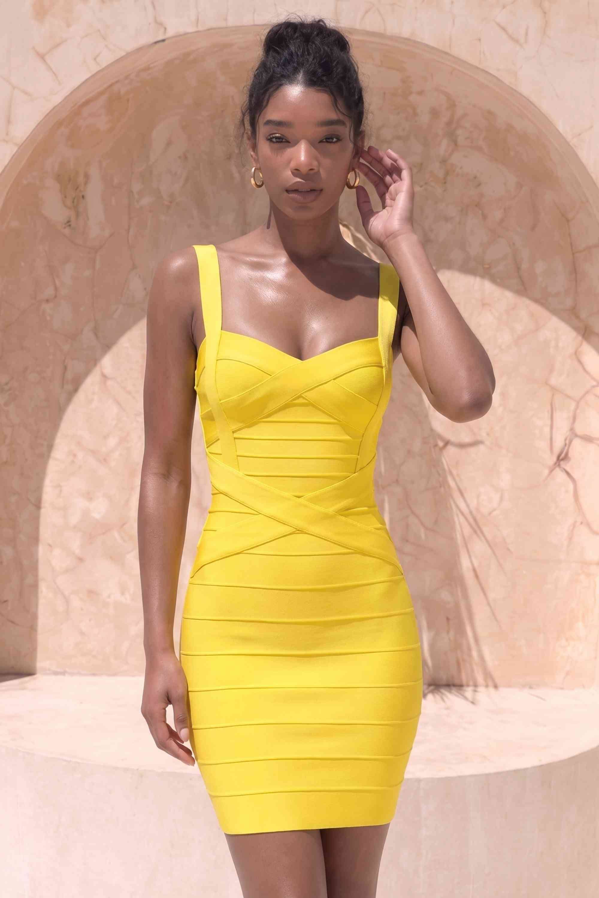 Woman wearing a figure flattering Heidi Bandage Mini Dress - Sun Yellow Bodycon Collection